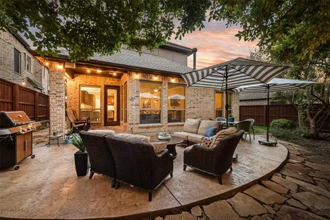 a view of a patio with couches table and chairs under an umbrella with a barbeque
