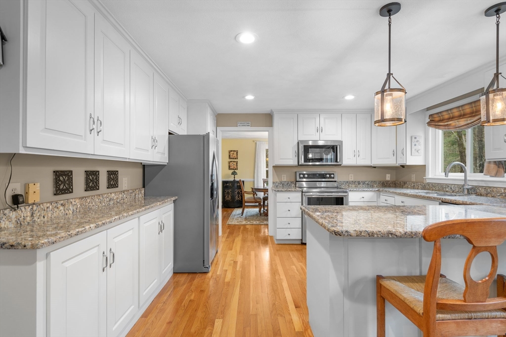 14 Hunters Road Boxford, MA 01921 - Photo 15 of 42 a kitchen with stainless steel appliances granite countertop a refrigerator a stove top oven a sink dishwasher and white cabinets with wooden floor