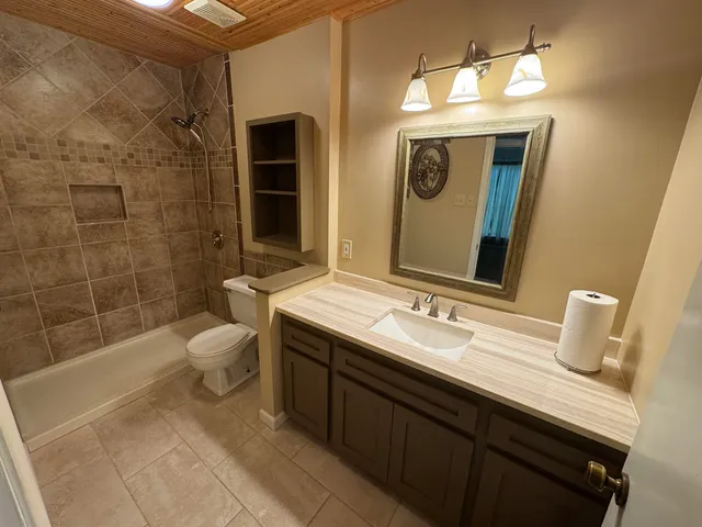 a bathroom with a granite countertop sink toilet and shower