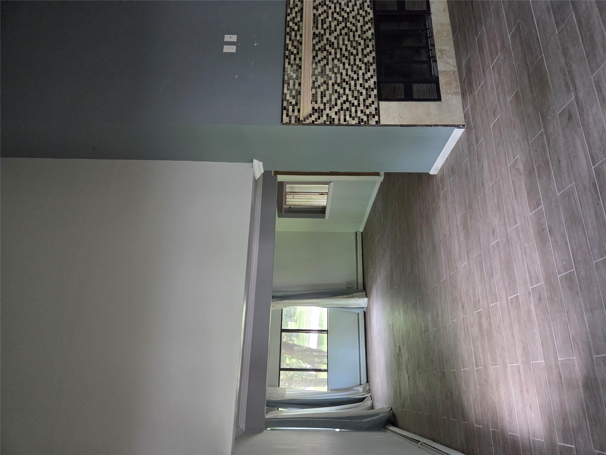 69 Mitchell Road Somers, NY 10589 - Photo 9 of 18 Spare room featuring a fireplace, wood tiled floors, a high ceiling, and a baseboard radiator