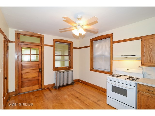 5110 West Roscoe Street Chicago, IL 60641 - Photo 5 of 10 a kitchen with stainless steel appliances granite countertop a stove a sink and a refrigerator with wooden floors