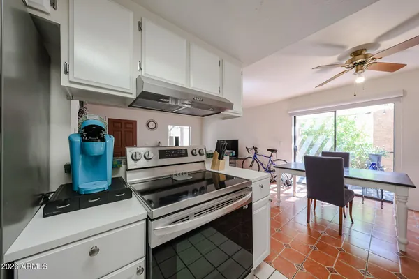 a kitchen with stainless steel appliances granite countertop a stove a refrigerator a dining table and chairs with the floor