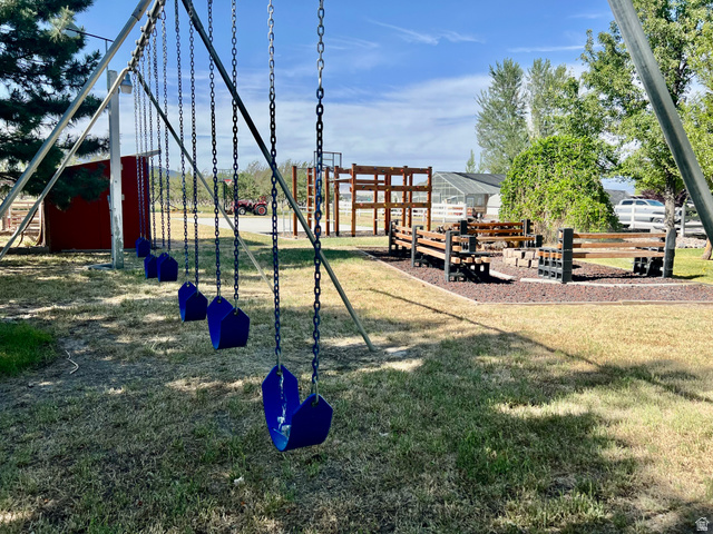 812 East Bates Cyn Road Tooele, UT 84074 - Photo 93 of 144 Expansive outdoor space featuring a multi-swing set, a fire pit area with built-in seating, a wooden play structure, and mature trees