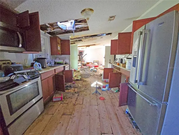 a kitchen with stainless steel appliances a stove a refrigerator a sink dishwasher and a dining table with wooden floor