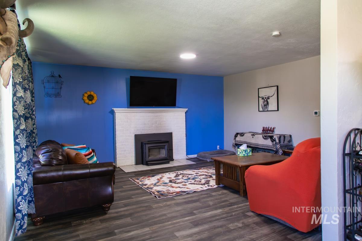 1404 Rochester Street Caldwell, ID 83605 - Photo 8 of 29 Living area featuring wood-finish flooring, a white brick fireplace with a dark insert, a white mantel, and a prominent blue accent wall