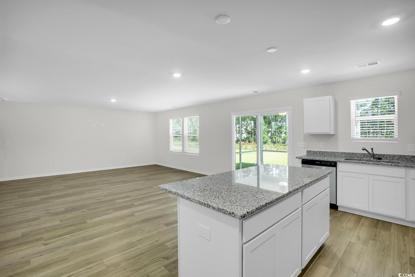 1113 Hainer Place Drive Conway, SC 29526 - Photo 6 of 28 Kitchen with white cabinets, light wood finished floors, a center island, light stone countertops, and stainless steel dishwasher