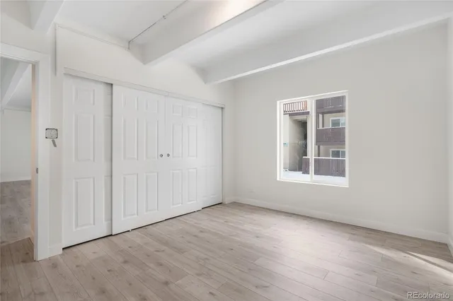 a view of an empty room with wooden floor & closet