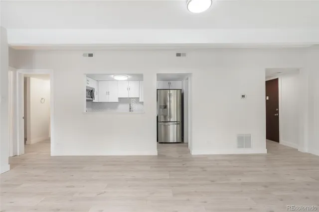 a view of an empty room with a window and wooden floor