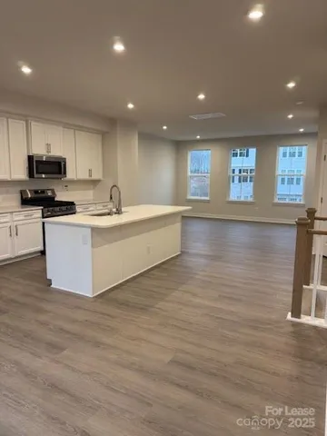 a large white kitchen with wooden floor