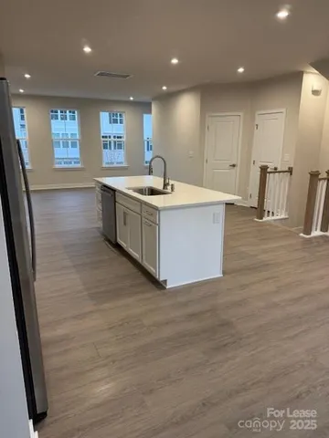 a large white kitchen with wooden floors and stainless steel appliances