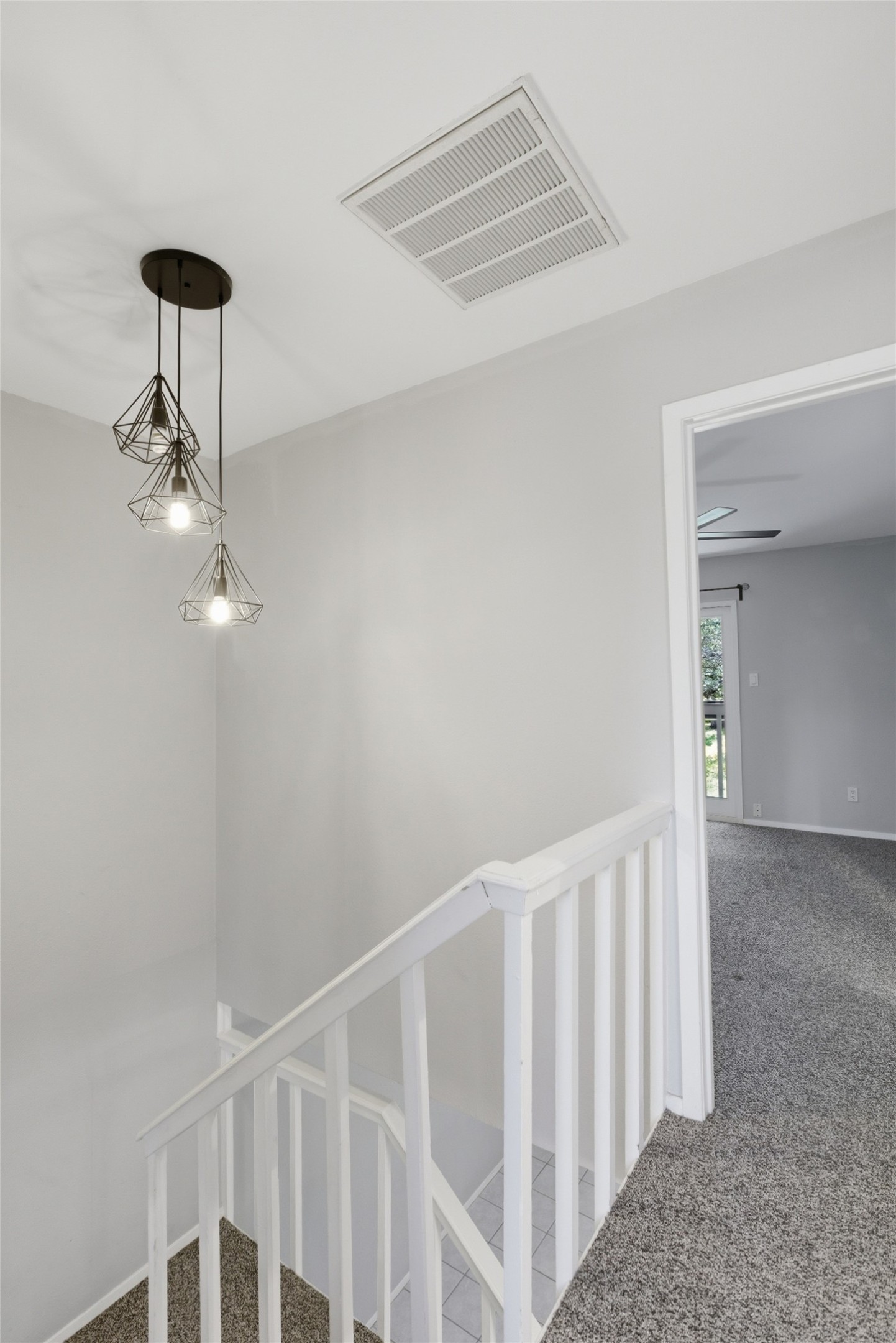 4204 Hudson Bend Road, Unit B Austin, TX 78734 - Photo 17 of 37 Staircase featuring white balusters and a complementary grey carpet, illuminated by a modern pendant light fixture with three geometric shades