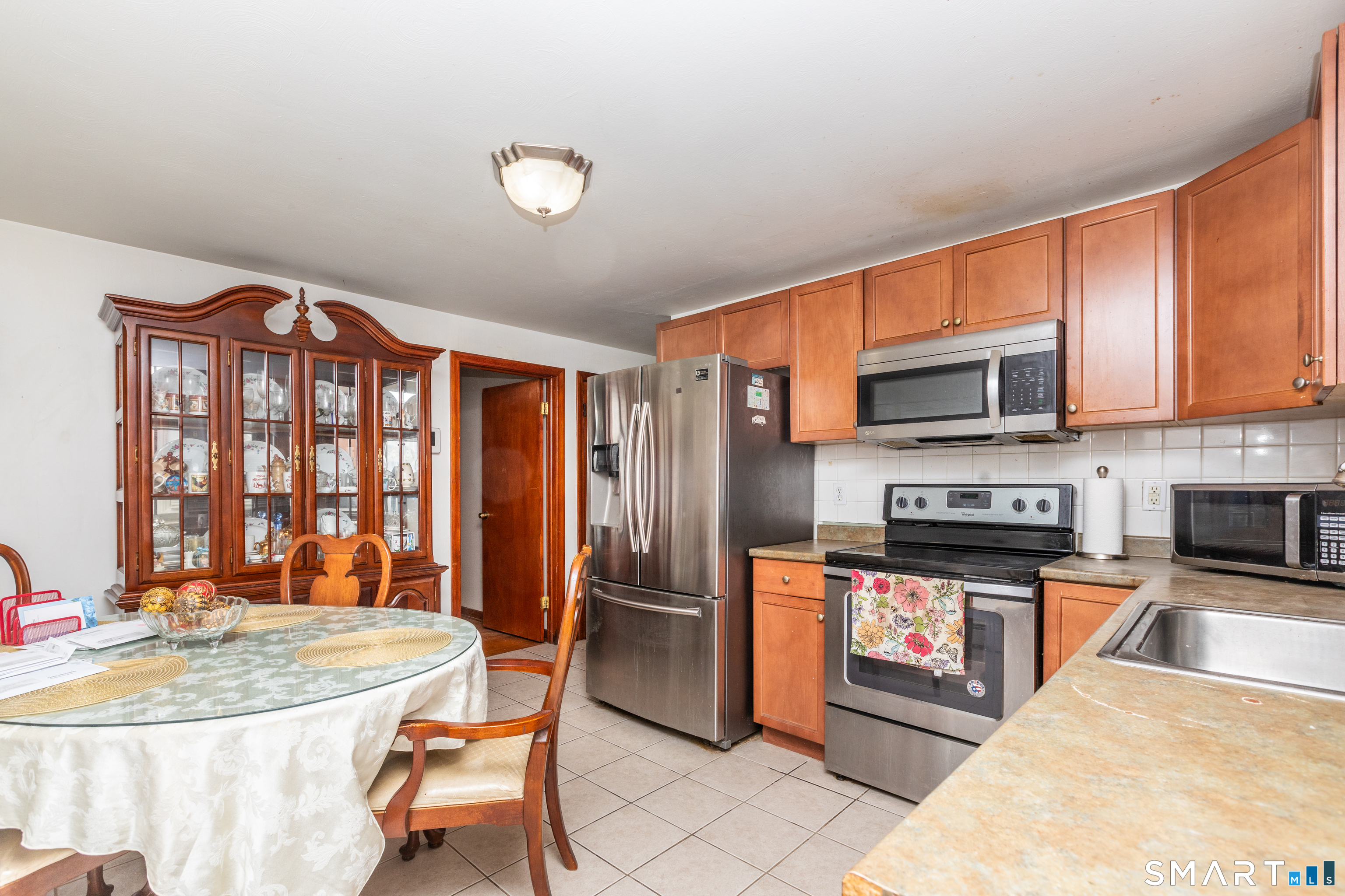 97 Benson Street New Britain, CT 06051 - Photo 7 of 24 a kitchen with stainless steel appliances granite countertop a stove top oven a sink dishwasher a dining table and chairs with wooden floor