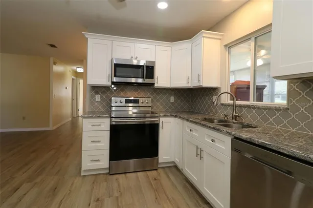 a kitchen with stainless steel appliances granite countertop a stove a sink and a microwave