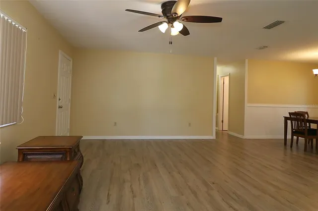 a view of a room with wooden floor and a ceiling fan