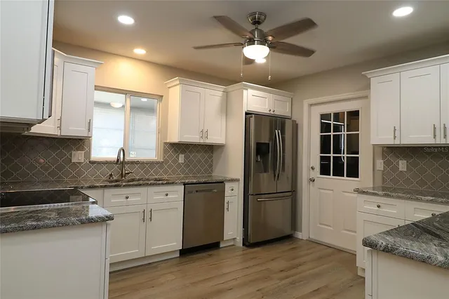 a kitchen with stainless steel appliances granite countertop a sink stove and refrigerator