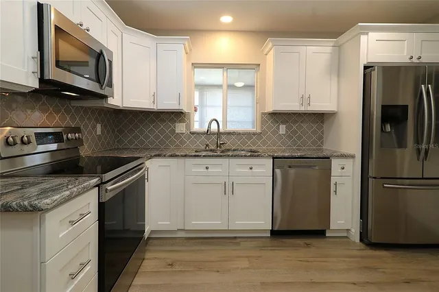 a kitchen with stainless steel appliances granite countertop a refrigerator microwave and sink