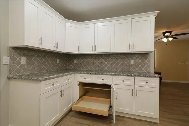 a kitchen with granite countertop white cabinets and a stove