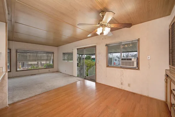 en empty room with wooden floor chandelier fan and windows