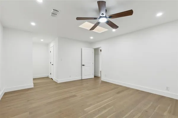 an empty room with wooden floor ceiling fan and windows