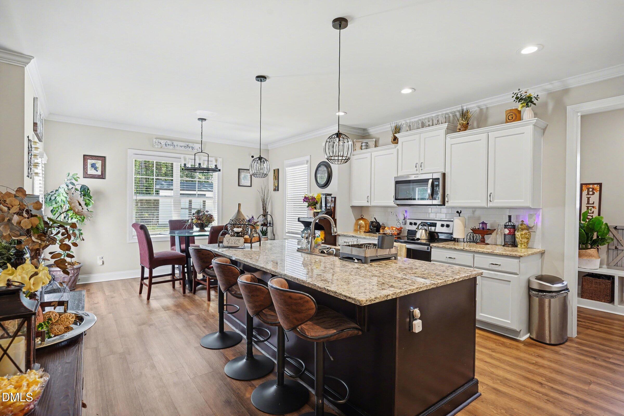 10 Mitchell Rdg Drive Youngsville, NC 27596 - Photo 6 of 38 a open kitchen with stainless steel appliances granite countertop a stove a sink dishwasher a microwave oven a dining table and chairs with wooden floor