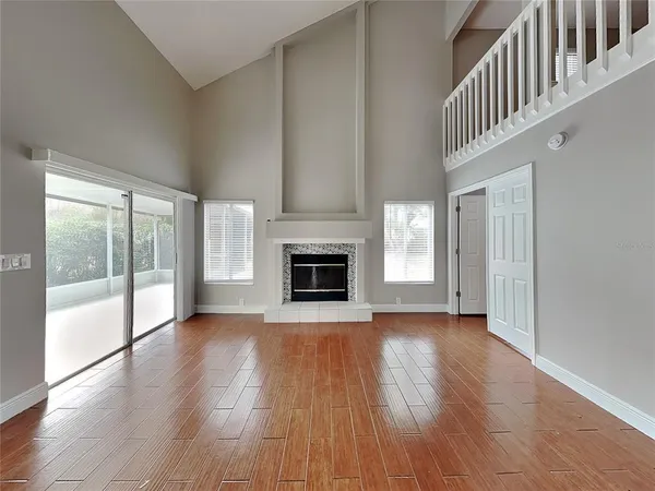 an empty room with wooden floor fireplace and windows