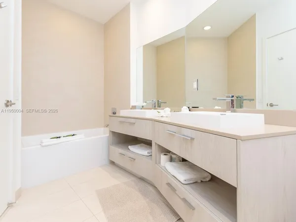 a bathroom with a double vanity sink a mirror and a bathtub
