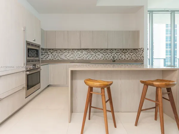 a kitchen with stainless steel appliances kitchen island a table chairs in it and white cabinets
