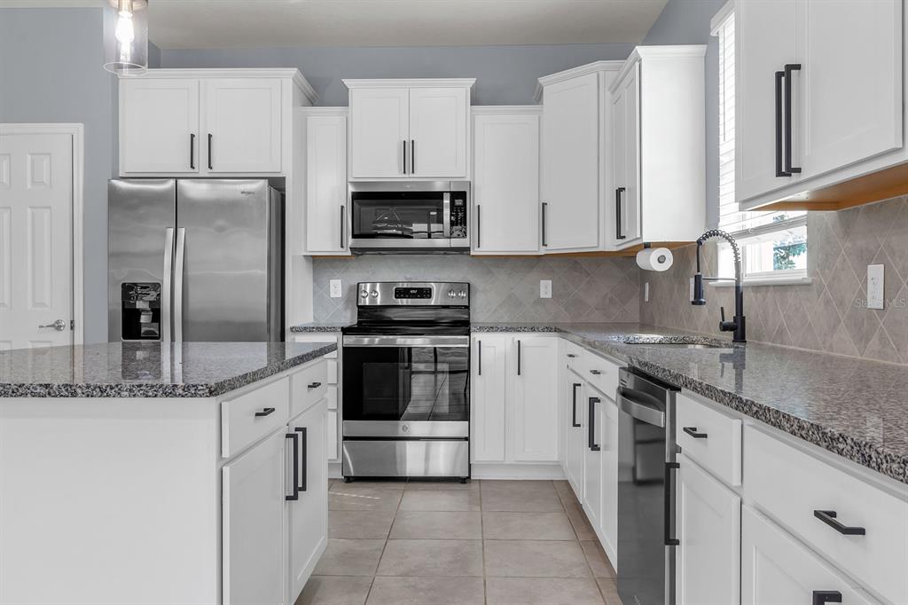 12653 Palapa Loop Spring Hill, FL 34610 - Photo 22 of 33 a kitchen with stainless steel appliances granite countertop a refrigerator sink and white cabinets