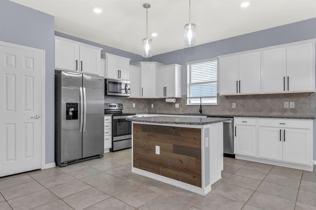 12653 Palapa Loop Spring Hill, FL 34610 - Photo 23 of 33 a kitchen with stainless steel appliances granite countertop a stove a sink and a refrigerator