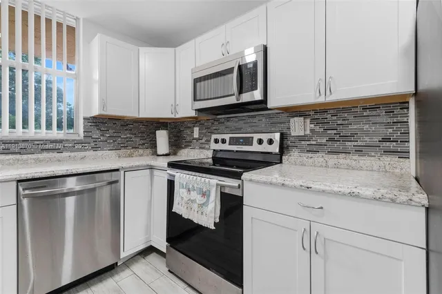 a kitchen with granite countertop white cabinets stainless steel appliances and a sink