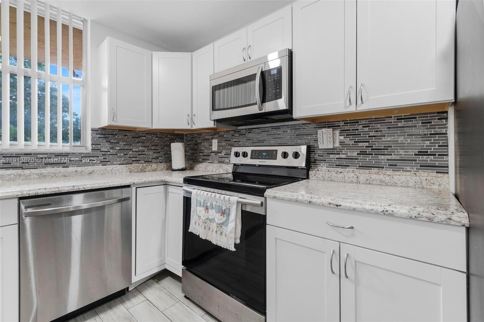 a kitchen with granite countertop white cabinets stainless steel appliances and a sink