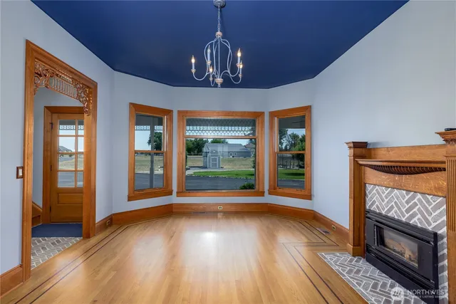 a view of an empty room with wooden floor fireplace and a window