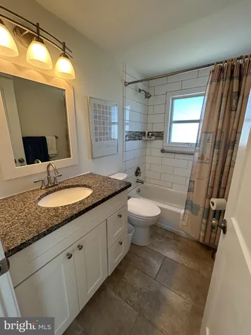 a bathroom with a granite countertop sink toilet and mirror