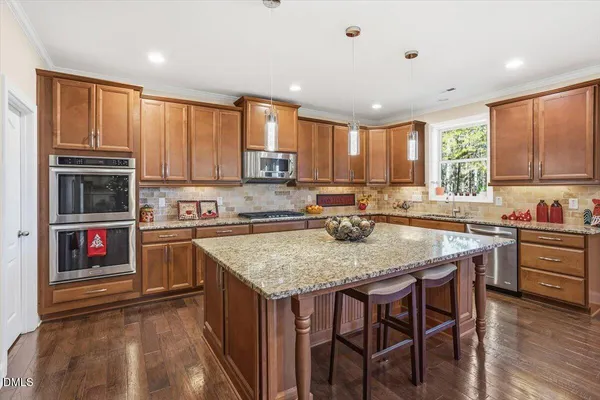 a kitchen with stainless steel appliances granite countertop a stove a sink and a refrigerator