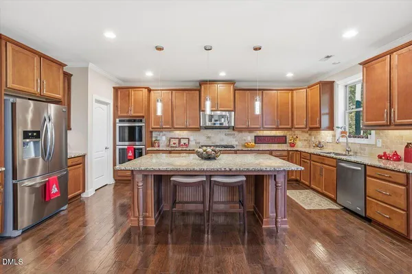 a kitchen with stainless steel appliances granite countertop a refrigerator a stove top oven a sink dishwasher and white cabinets with wooden floor