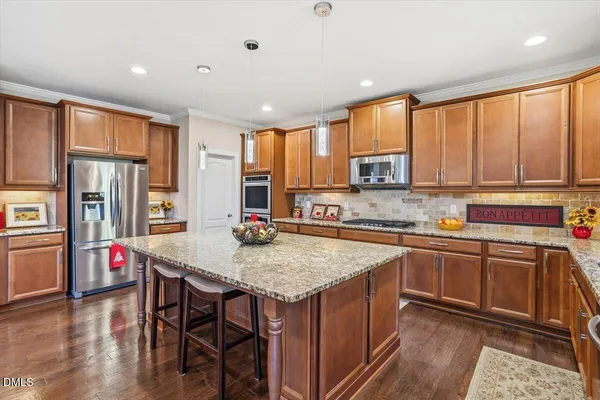 a kitchen with granite countertop a stove a sink dishwasher and a refrigerator with wooden floor