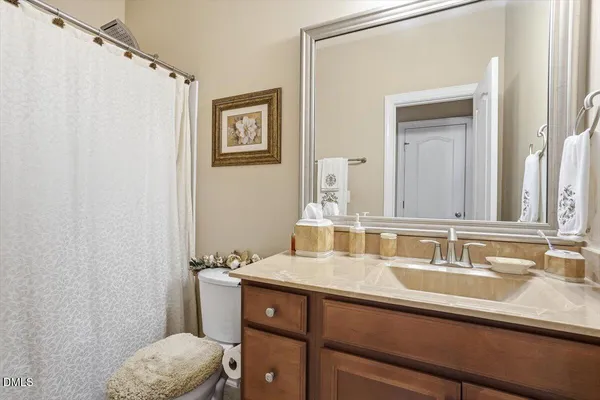a bathroom with a granite countertop sink and a toilet
