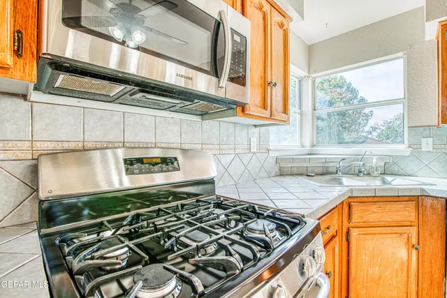 a kitchen with stainless steel appliances kitchen island granite countertop a stove a sink and a refrigerator