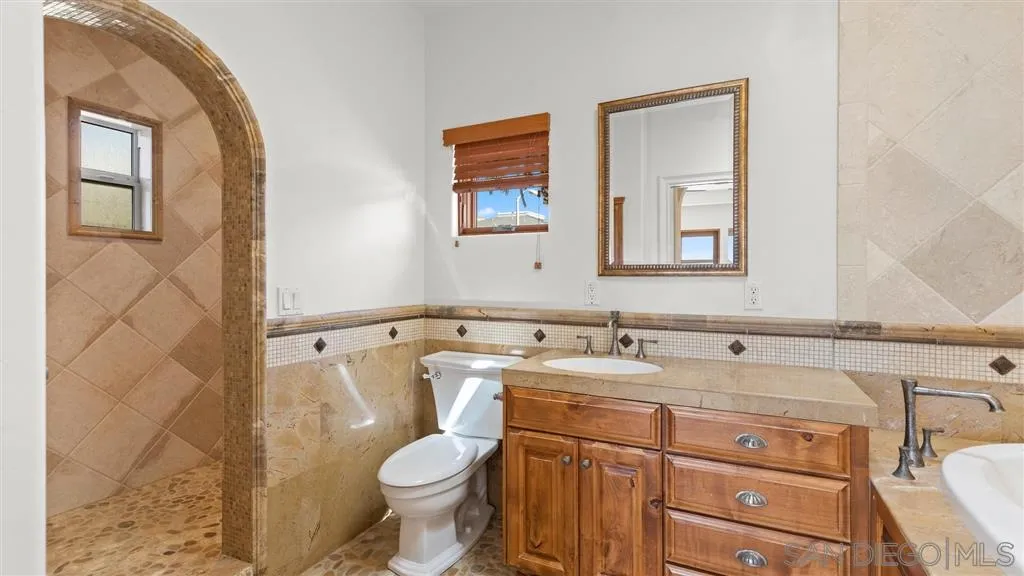 5730 Dolphin Place La Jolla, CA 92037 - Photo 15 of 19 a bathroom with a granite countertop toilet sink and mirror