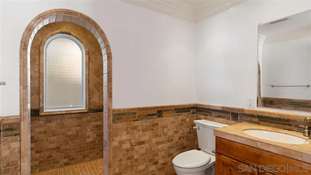 5730 Dolphin Place La Jolla, CA 92037 - Photo 7 of 19 a bathroom with a granite countertop toilet a sink and a mirror