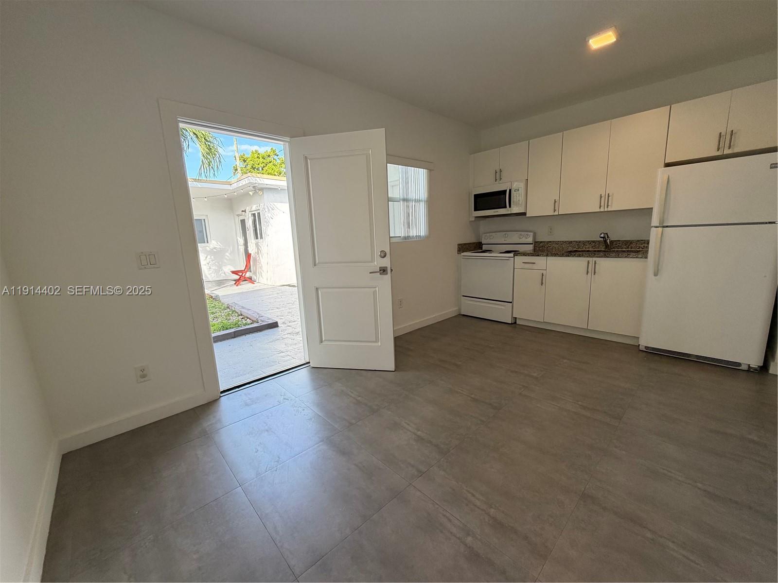 3051 Southwest 27th Lane, Unit 3 Miami, FL 33133 - Photo 3 of 8 a kitchen with stainless steel appliances granite countertop a refrigerator sink and white cabinets