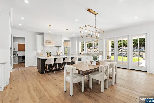 a view of a dining room and livingroom with furniture wooden floor a rug a chandelier