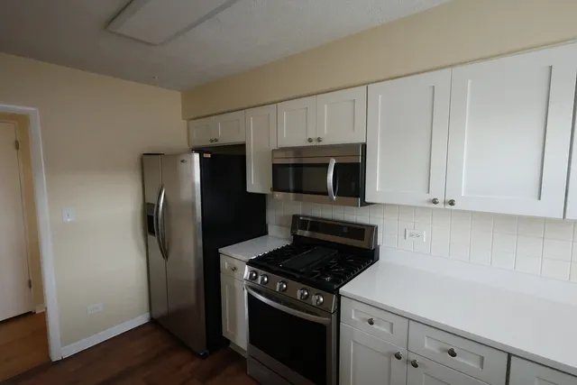 a kitchen with white cabinets and stainless steel appliances