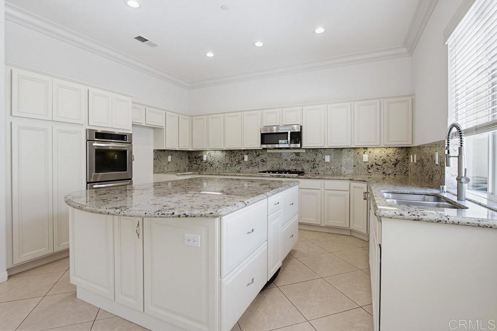 672 Inverlochy Drive Fallbrook, CA 92028 - Photo 21 of 75 a kitchen with kitchen island granite countertop white cabinets sink and stainless steel appliances