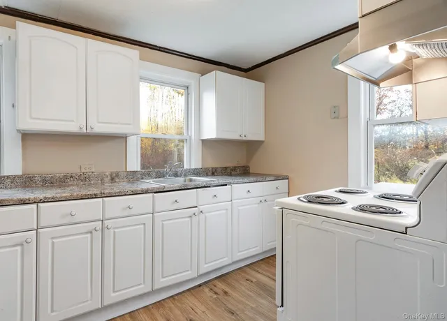 a kitchen with granite countertop white cabinets sink and window
