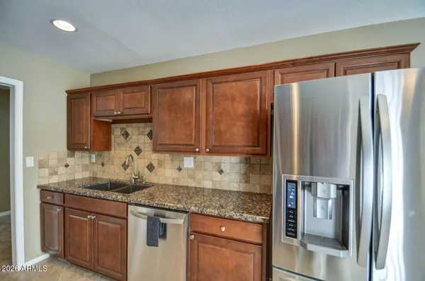 a kitchen with granite countertop a refrigerator and cabinets