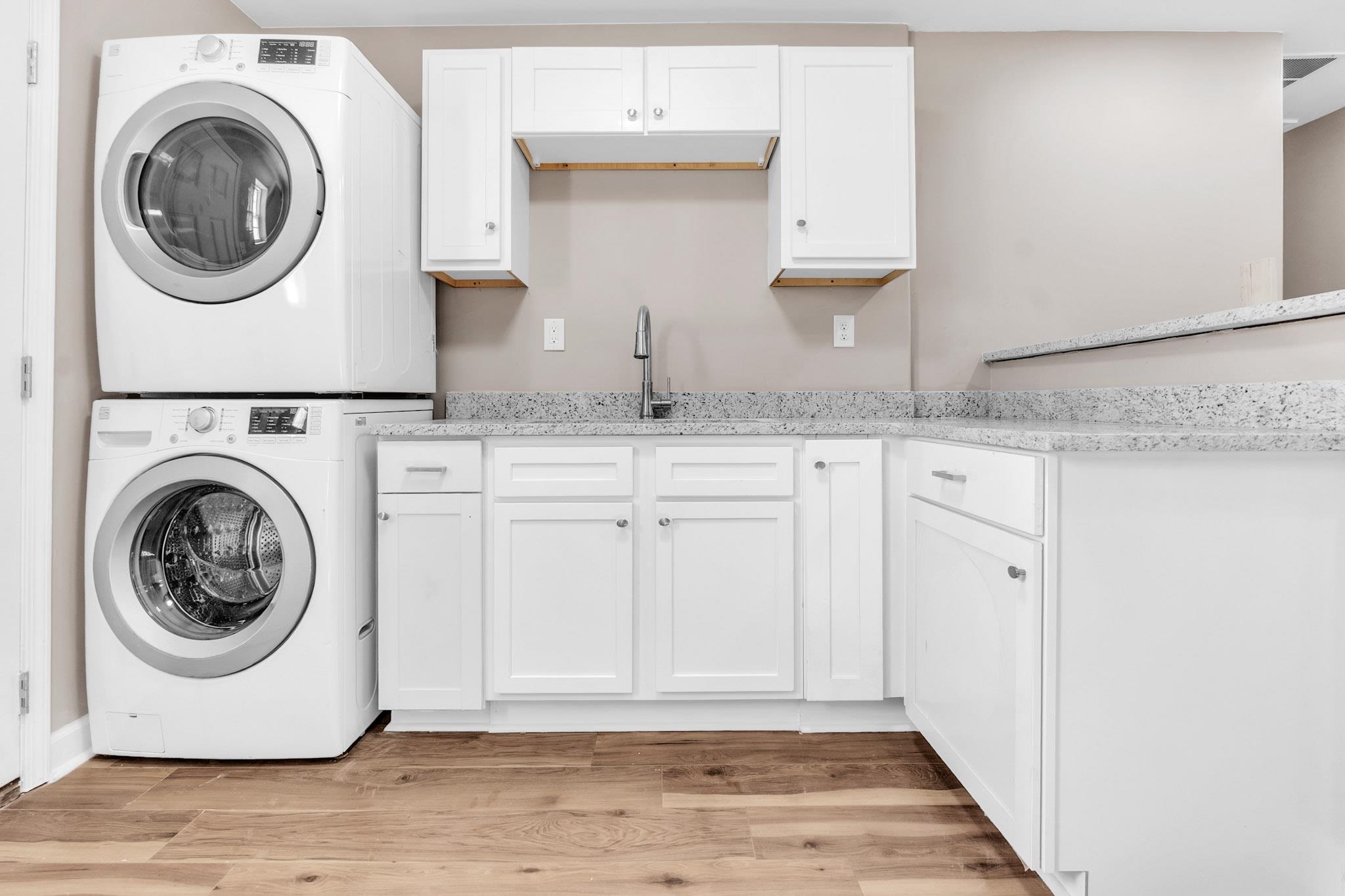 375 Pope Street Memphis, TN 38112 - Photo 12 of 19 Laundry room featuring stacked washing machine and dryer, light wood-style flooring, and cabinet space