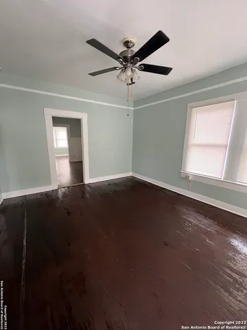 a view of wooden floor and a chandelier fan in a room