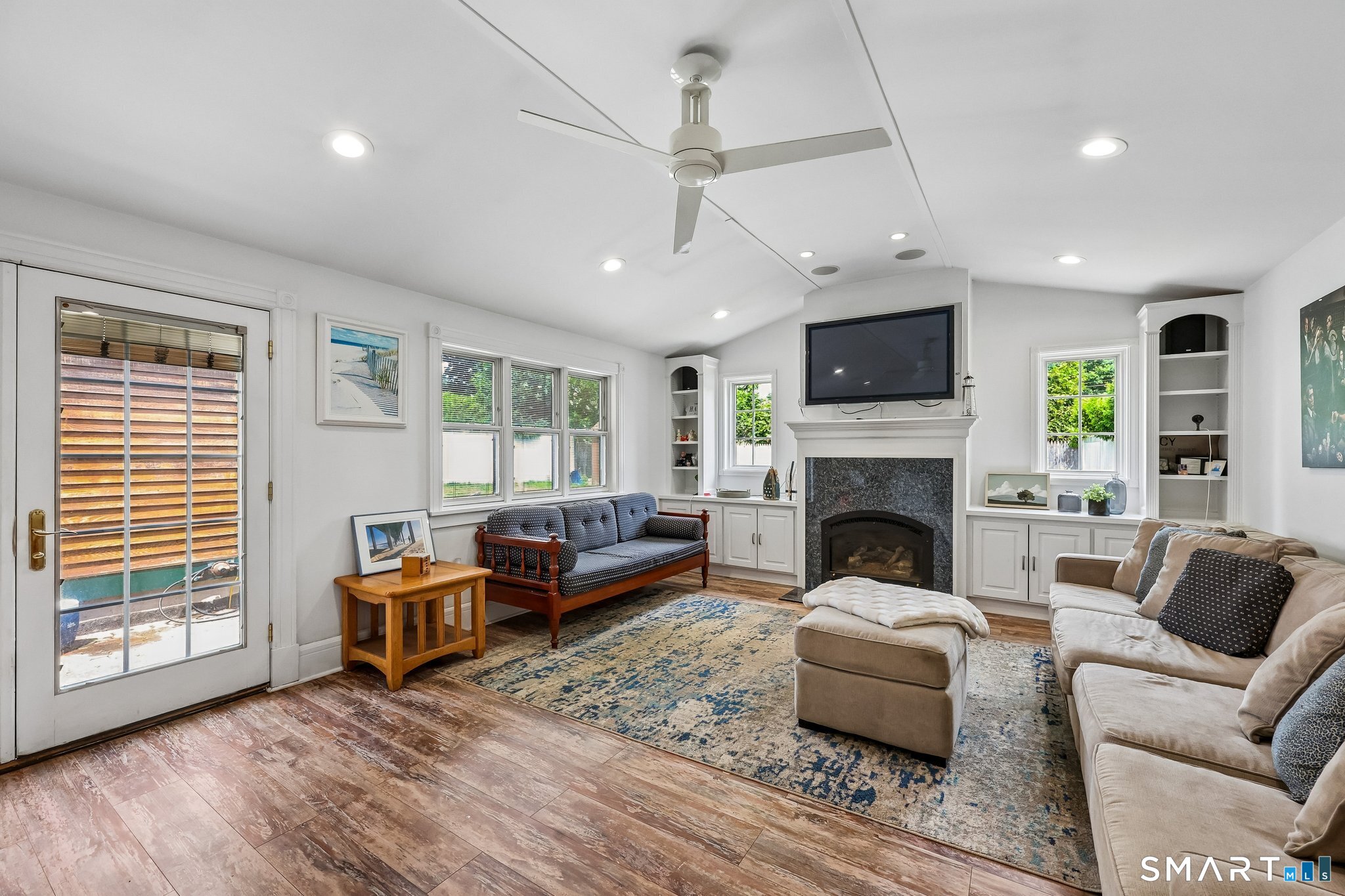 21 Friendly Road Norwalk, CT 06851 - Photo 2 of 28 Relax and unwind in this expansive Living Room with gas fireplace, plenty of light-filled windows and French doors to a patio. Built-ins add charm and vaulted ceilings make this room feel enormous! Recessed lighting and ceiling fans included.