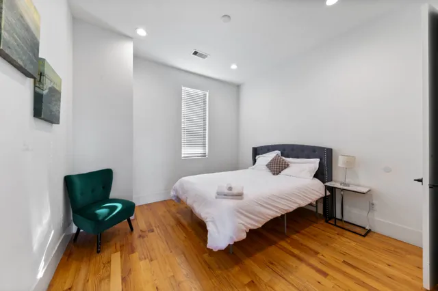 a bedroom with a bed windows and wooden floor